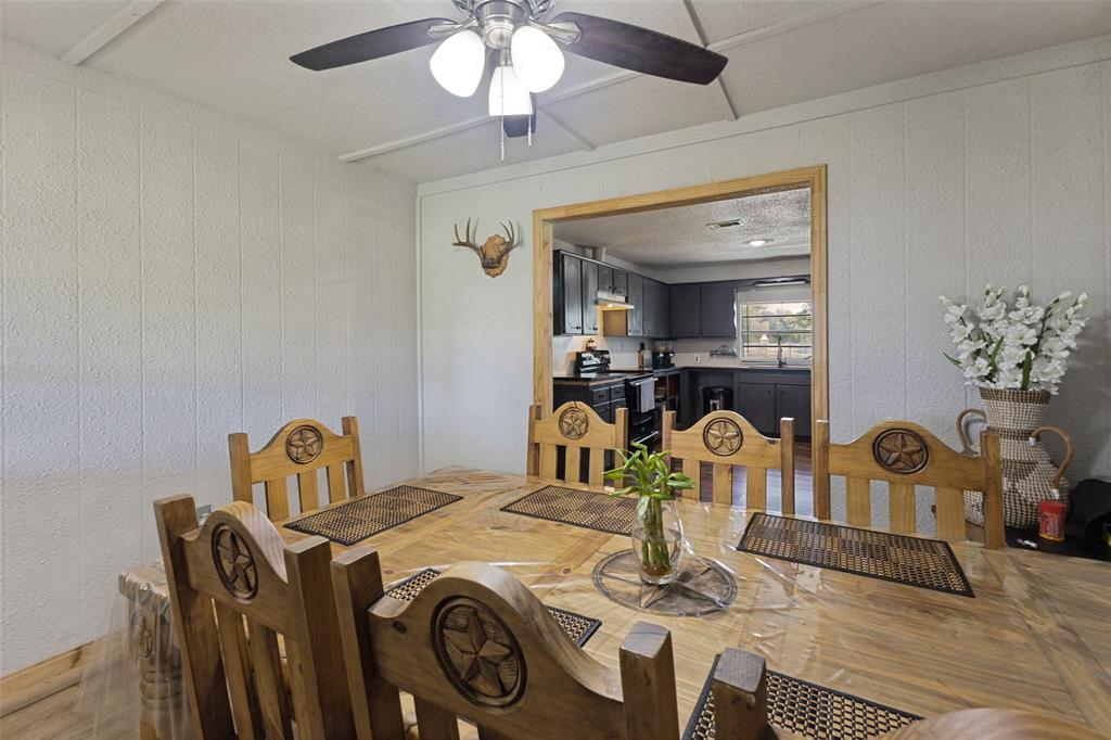 Dining area featuring a central ceiling fan with multi-light fixture, wood-finish flooring, and a wide doorway framed in natural wood trim