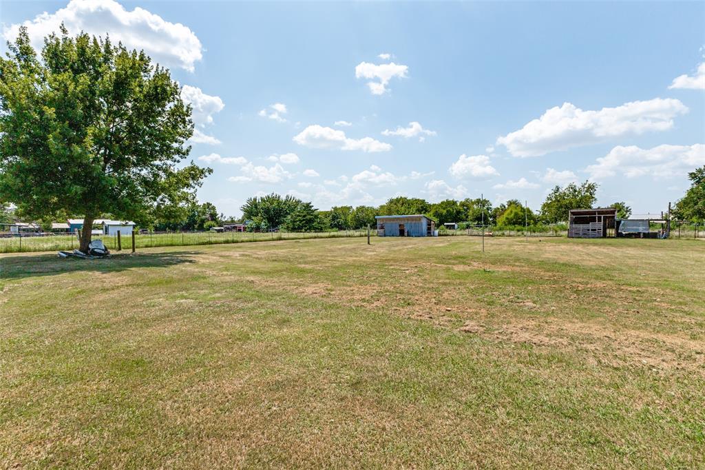 Expansive level acreage featuring mature trees, wire perimeter fencing, and multiple outbuildings