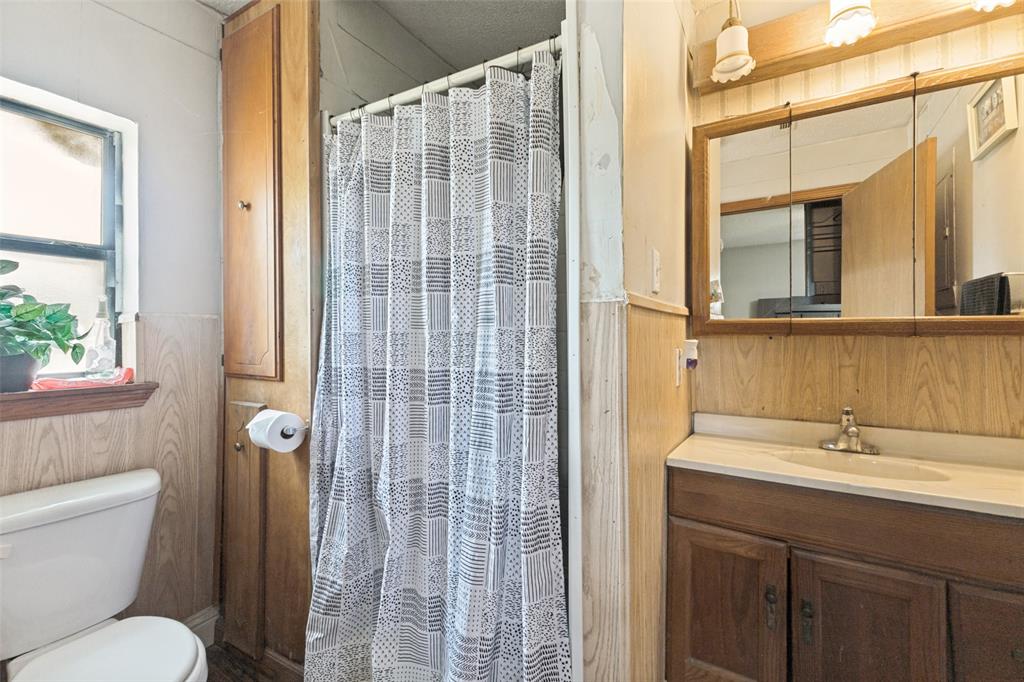 Bathroom featuring wood-finish cabinetry, a built-in linen storage unit, a countertop-integrated basin, and a tri-panel mirrored medicine cabinet