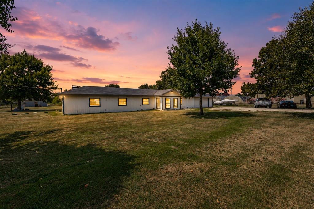 Single-story exterior featuring light-toned horizontal siding, a pitched roofline, and expansive grounds with mature trees Single-story exterior featuring light-toned horizontal siding, a pitched roofline, and expansive grounds with mature trees