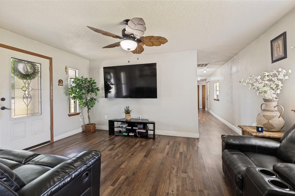 Wood-finish flooring, ceiling fan with light fixture, and door featuring decorative glass inlay