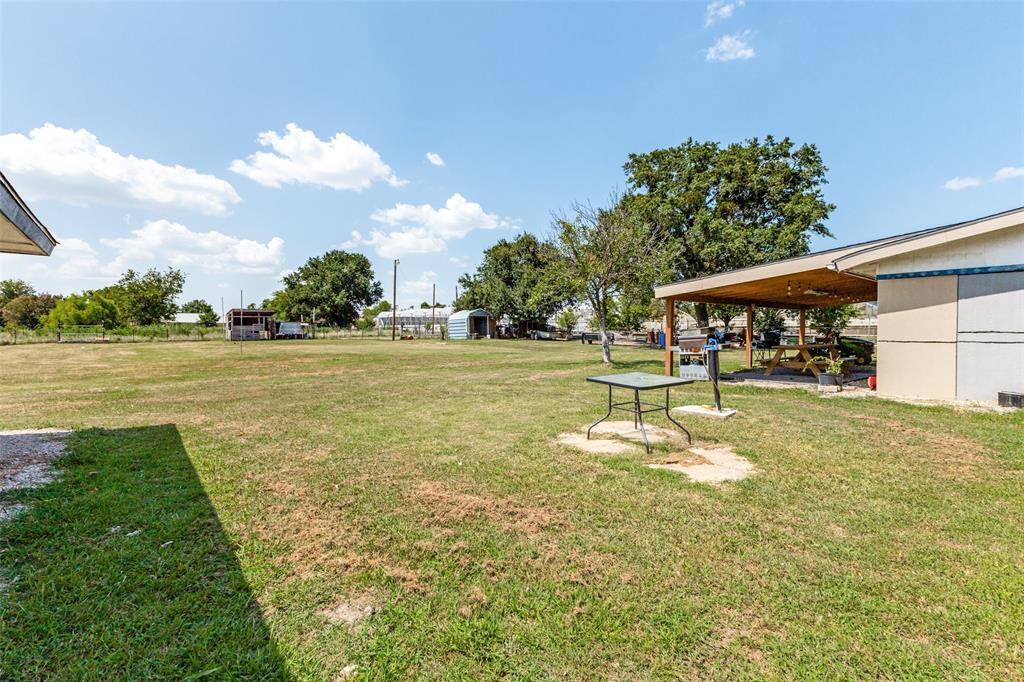 Expansive grass lot featuring a covered patio and mature trees