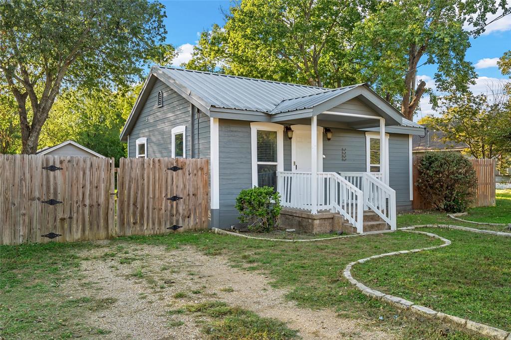 Exterior featuring horizontal siding, a metal roof, a covered front porch with white railing, and a fenced-in yard Exterior featuring horizontal siding, a metal roof, a covered front porch with white railing, and a fenced-in yard