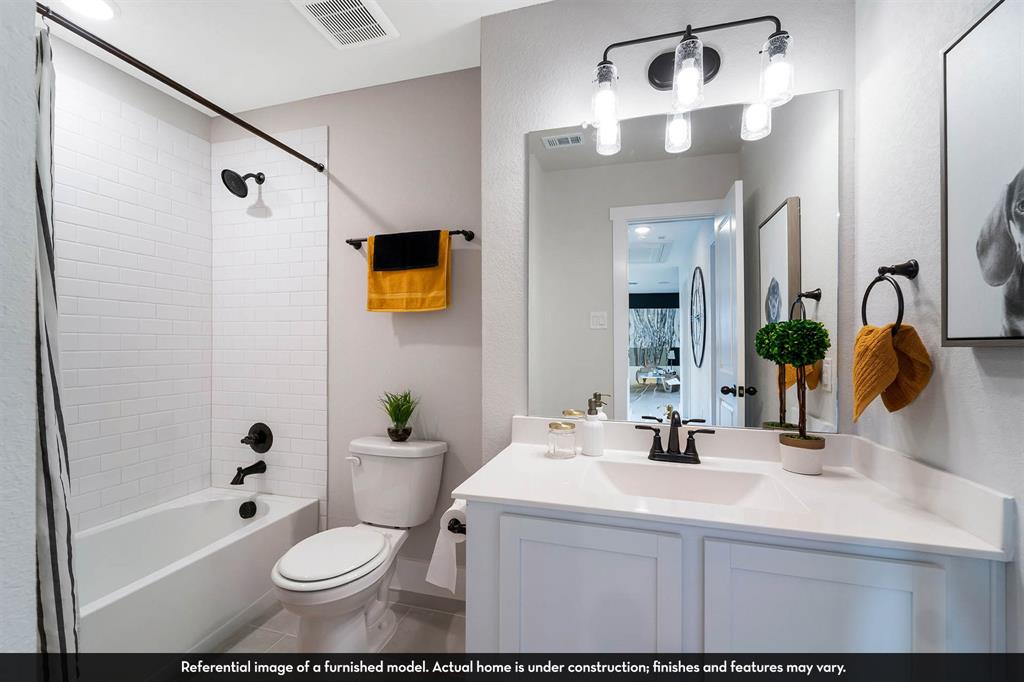 Bathroom featuring a white vanity with a rectangular sink, matte black hardware, a subway tile shower surround, and a four-light fixture above a large mirror