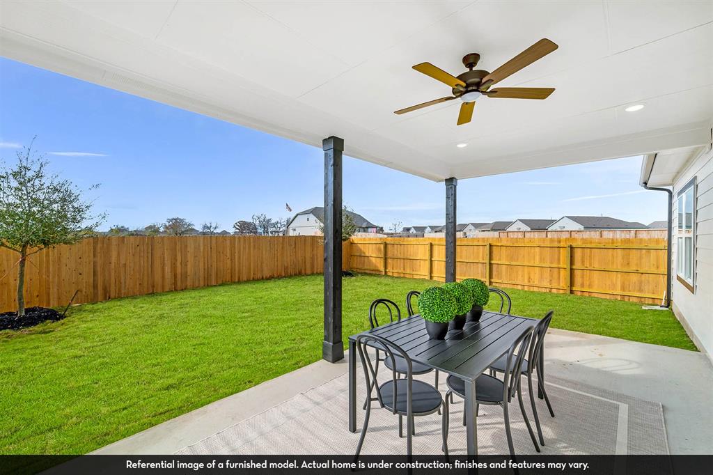 Covered concrete patio featuring dark support pillars, a ceiling-mounted fan, recessed lighting, and an enclosed wood privacy fence