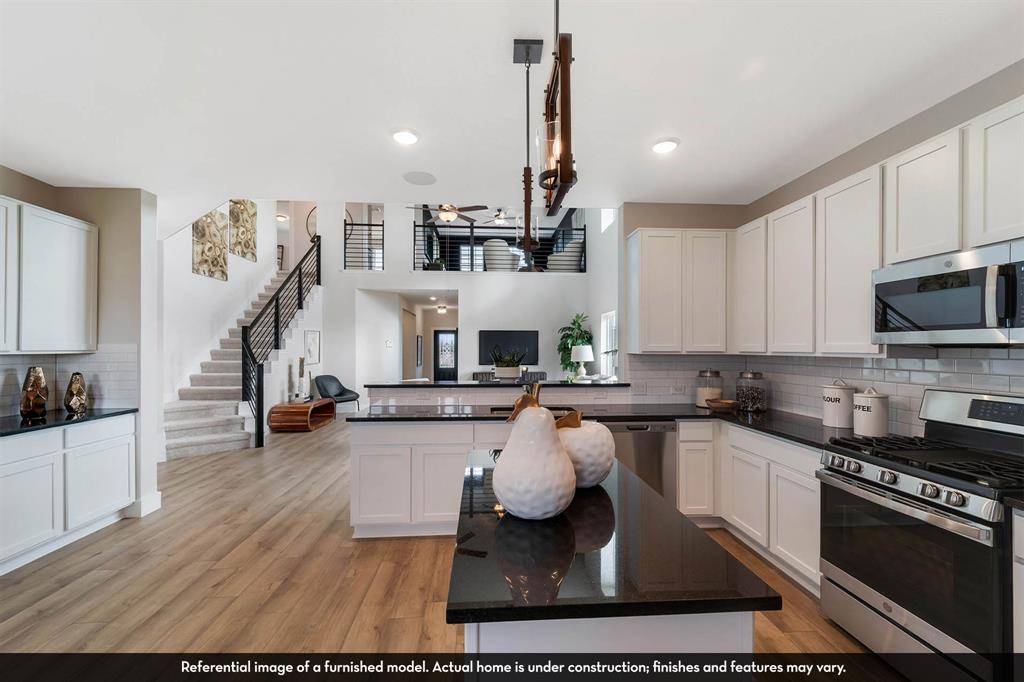 Kitchen featuring white shaker-style cabinetry, dark stone countertops, stainless steel appliances, central island, and wood-finish flooring
