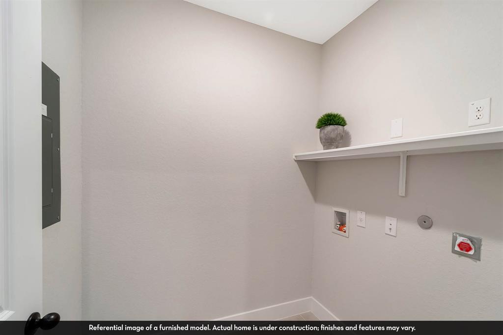 Utility space featuring a built-in shelf, recessed electrical panel, and designated plumbing connections