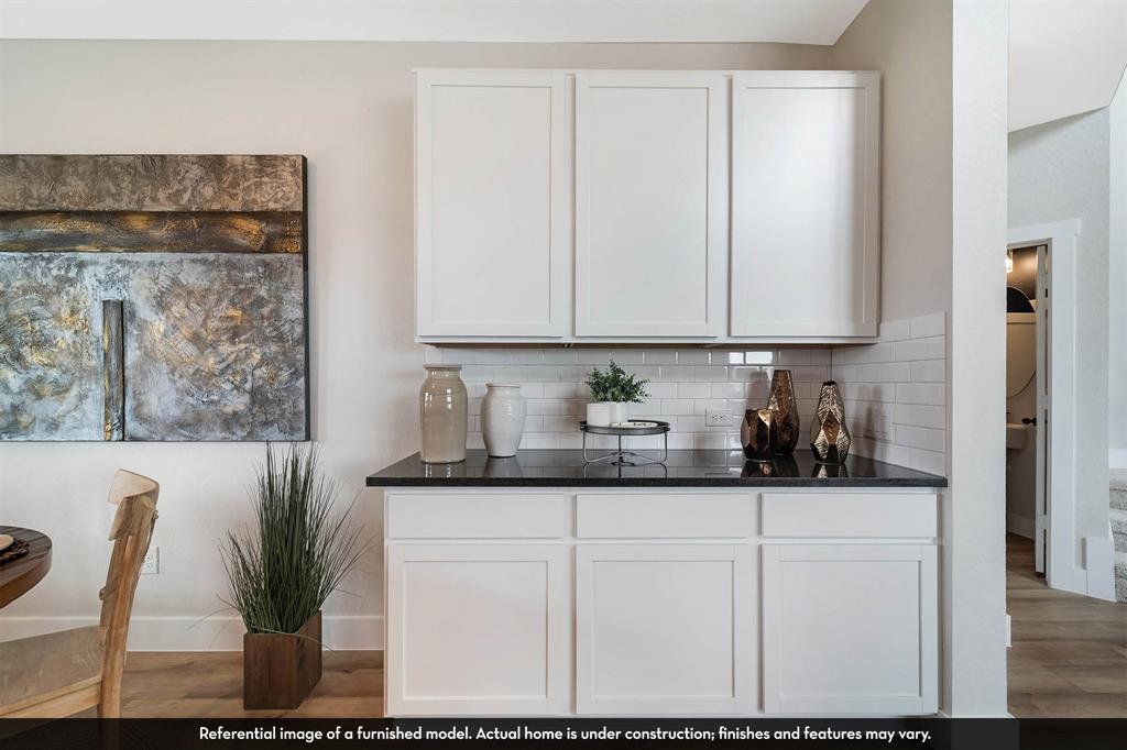 Built-in cabinetry featuring white Shaker-style doors, dark stone-finish countertops, and a white subway tile backsplash