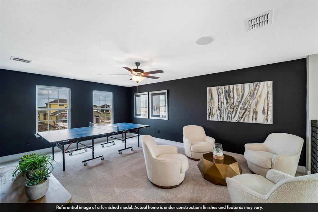 Spacious room featuring dark-toned accent walls, recessed lighting, a ceiling fan with integrated light fixture, and large windows with multi-pane glass