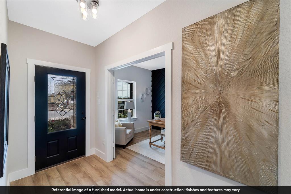 Entryway featuring a dark-toned front door with decorative glass paneling, wood-finish flooring, and crisp white door casings
