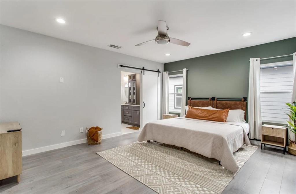Room featuring wood-finish flooring, recessed lighting, a modern ceiling fan, an accent wall, and a sliding barn door Room featuring wood-finish flooring, recessed lighting, a modern ceiling fan, an accent wall, and a sliding barn door
