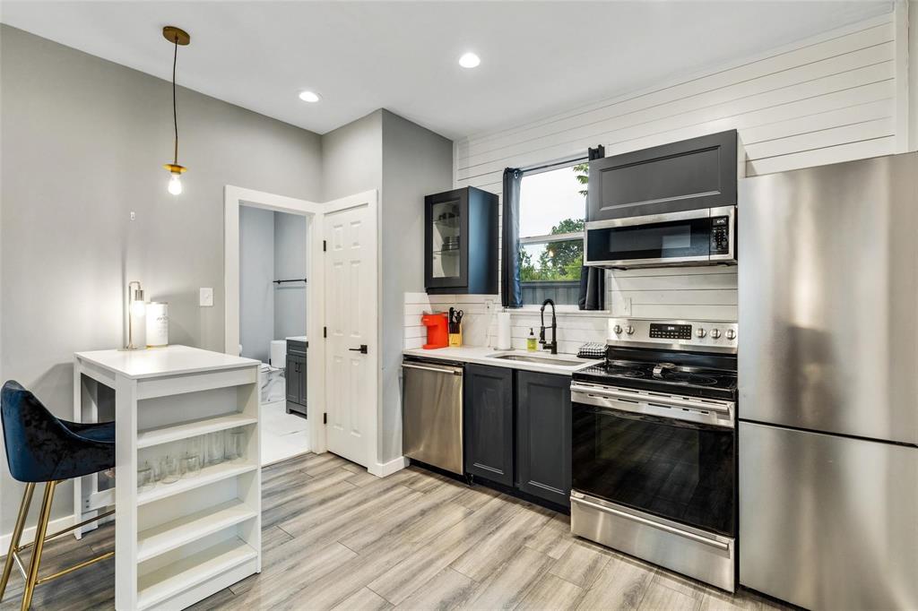 Kitchen featuring dark-finish cabinetry, stainless steel appliances, wood-finish flooring, horizontal wall paneling, and recessed lighting