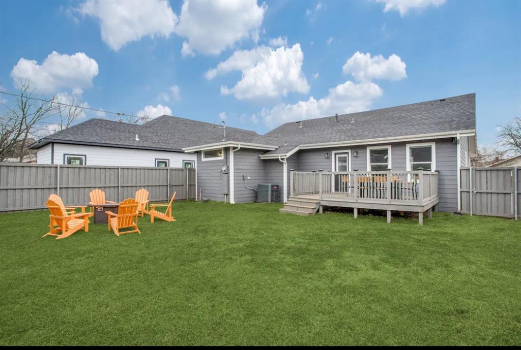 Fenced backyard featuring an elevated wood deck and a level lawn