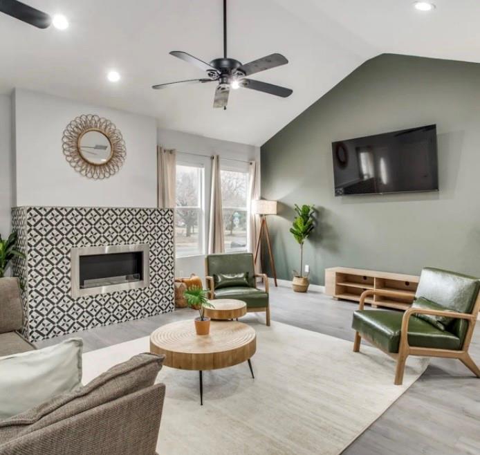 Vaulted ceilings with recessed lighting, a fireplace featuring patterned tile surround, and wood-finish flooring Vaulted ceilings with recessed lighting, a fireplace featuring patterned tile surround, and wood-finish flooring