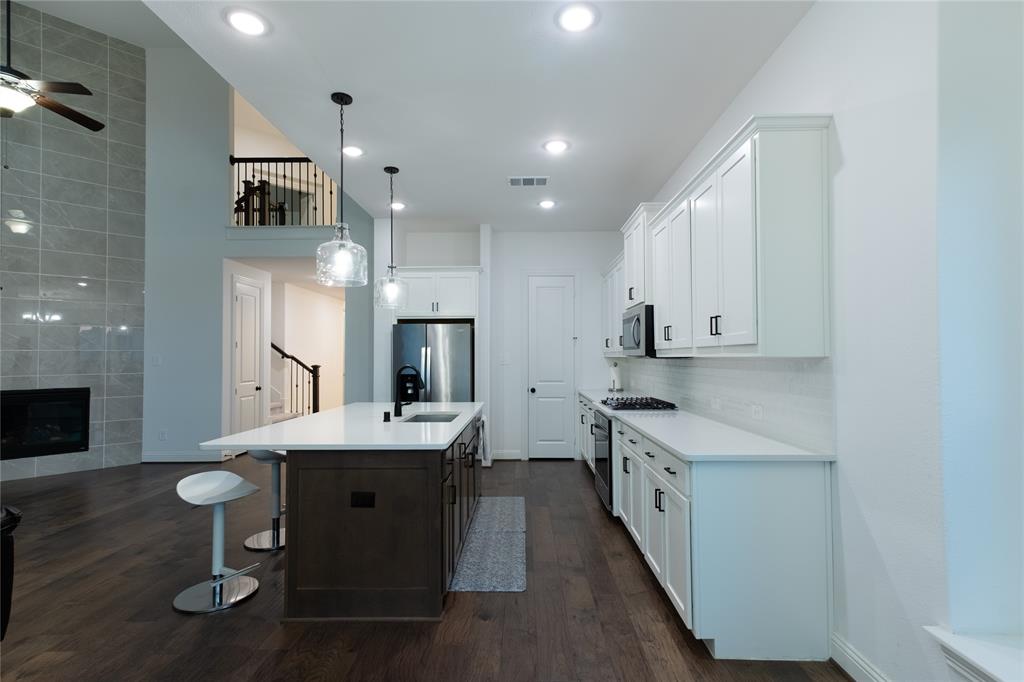 Kitchen featuring white cabinetry, center island with stone-finish countertop, stainless steel appliances, and dark wood-finish flooring
