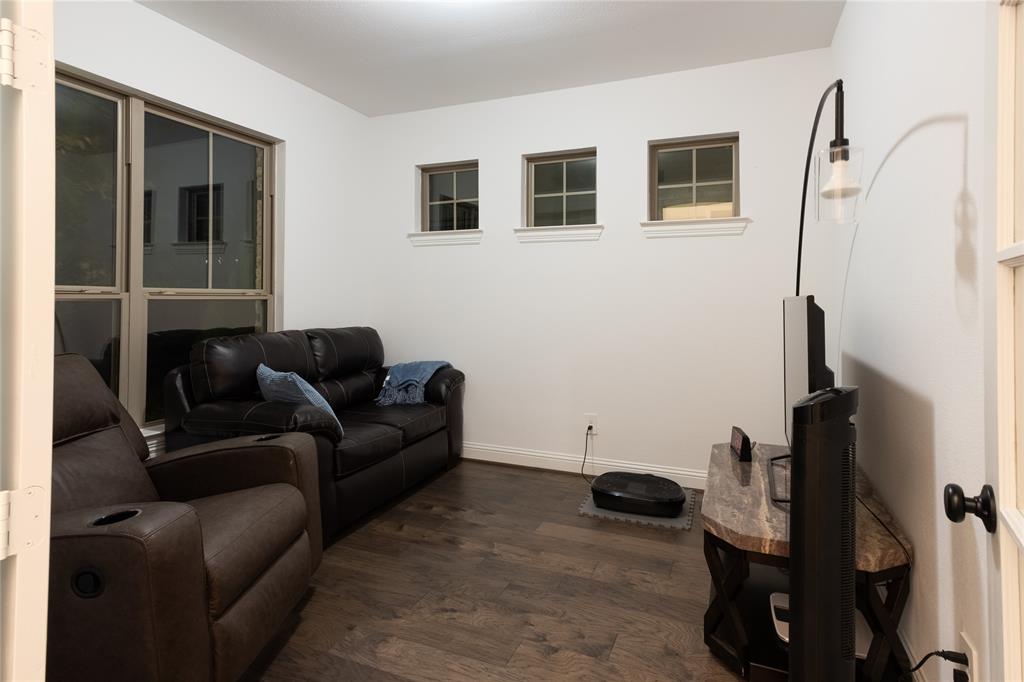 Room featuring wood-finish flooring, three upper-wall square windows with muntin detailing, a large rectangular window, and a glass-paneled entry door