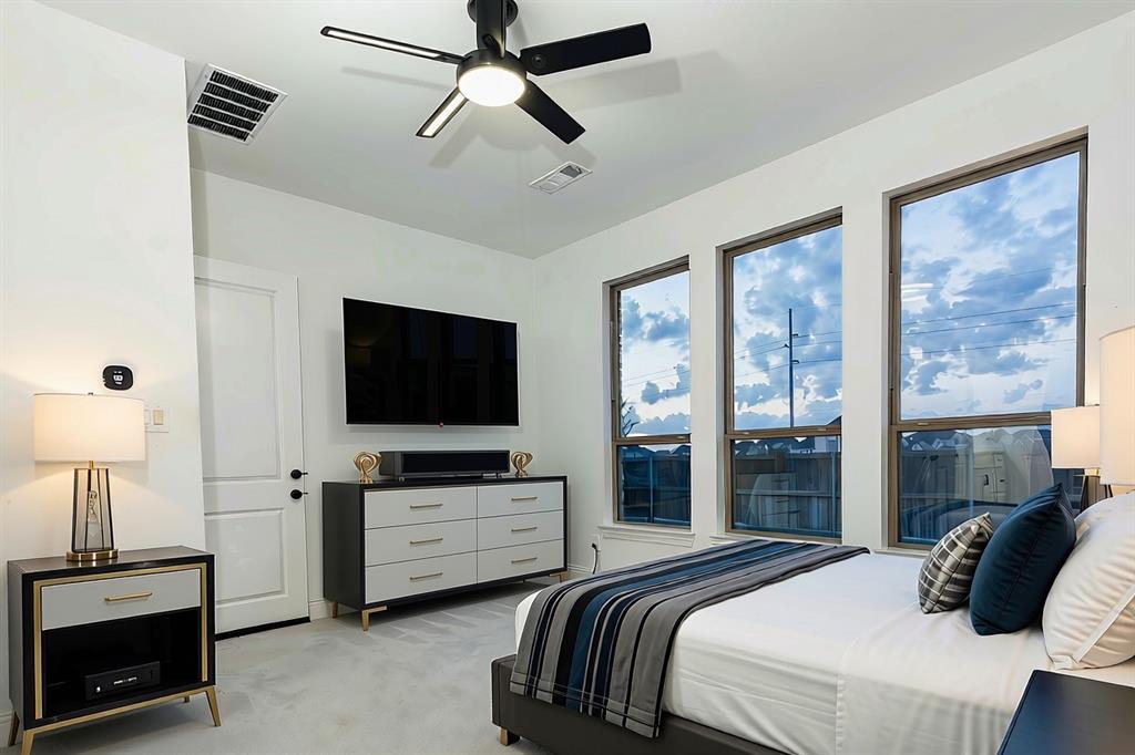 Bedroom concept featuring three large windows, neutral wall color, and a matte black ceiling fan with an integrated light fixture