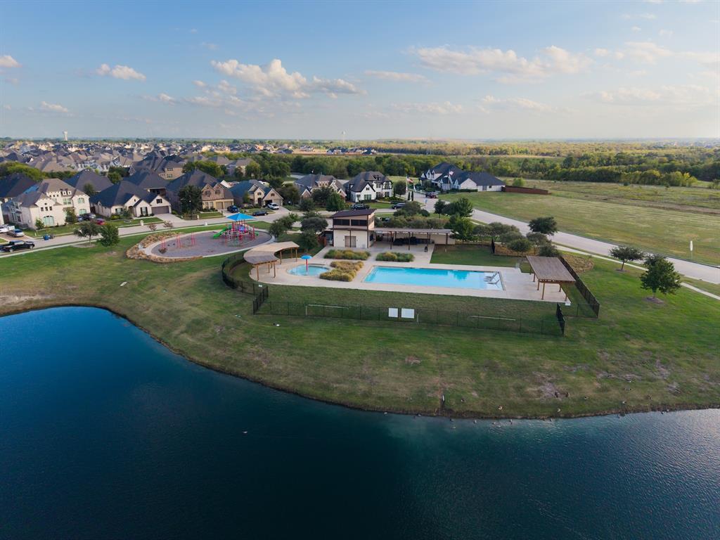 Recreational facility featuring an in-ground swimming pool, a separate spa, stone-paver decking, covered pergolas, and a children's play area situated along a waterfront