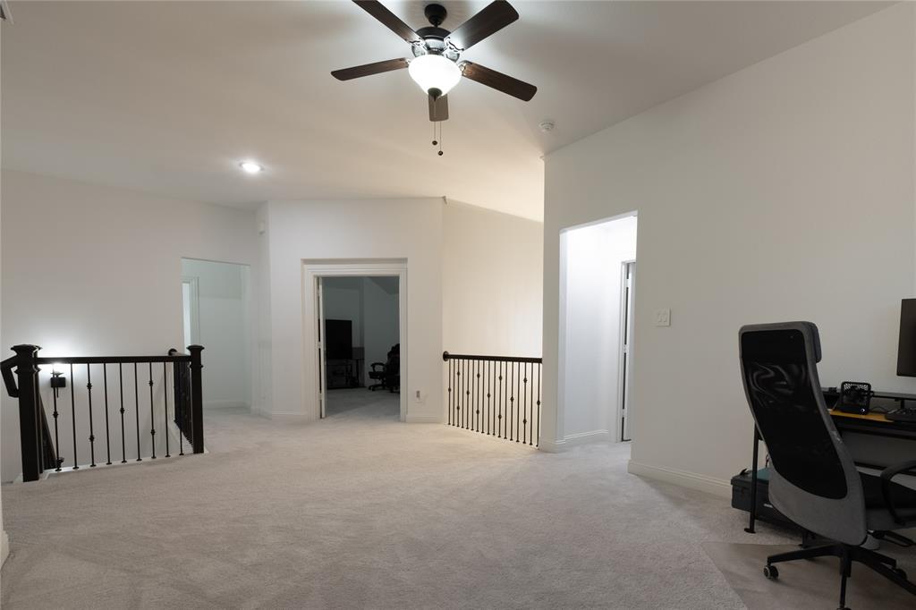 Open-concept space featuring neutral carpeting, a ceiling fan with integrated lighting, recessed lighting, and metal balustrade railings