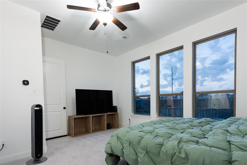 Three expansive, vertically-oriented windows, neutral wall coloring, and a five-blade ceiling fan with integrated lighting