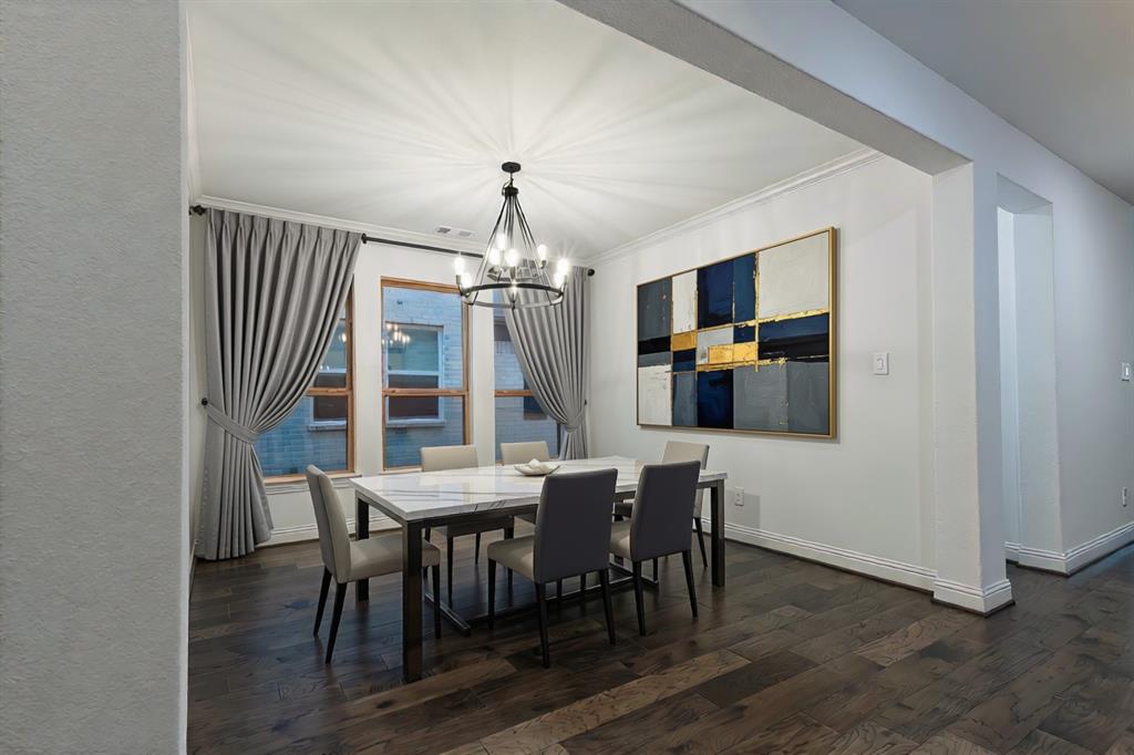 Dining area featuring wood-finish flooring, a multi-arm iron chandelier, and oversized windows with window treatments