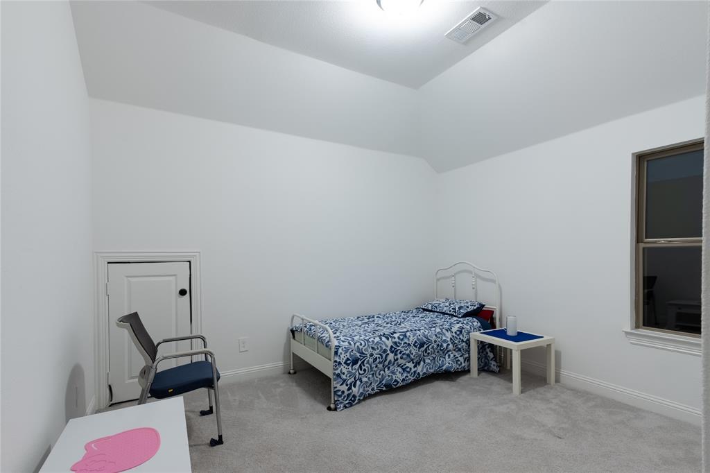 Vaulted ceiling featuring neutral wall paint, carpeted flooring, and a dedicated attic access panel