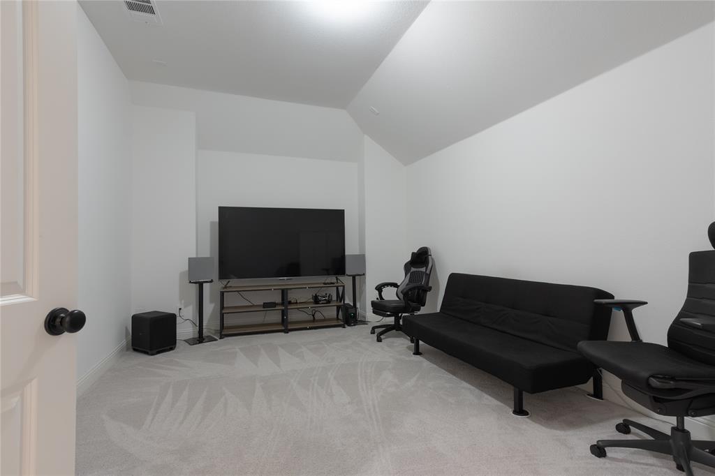 Neutral-toned room featuring a vaulted ceiling and wall-to-wall carpeting