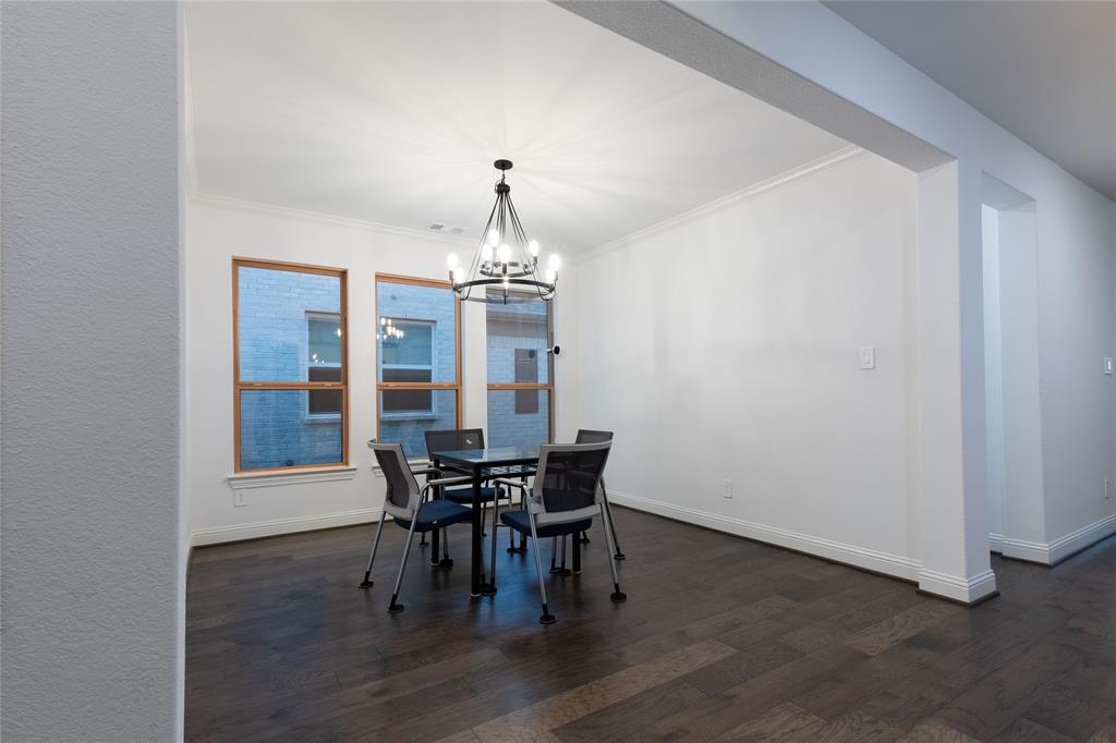 Dark wood-finish flooring, three large windows with wood-tone frames, and an industrial-style multi-bulb chandelier