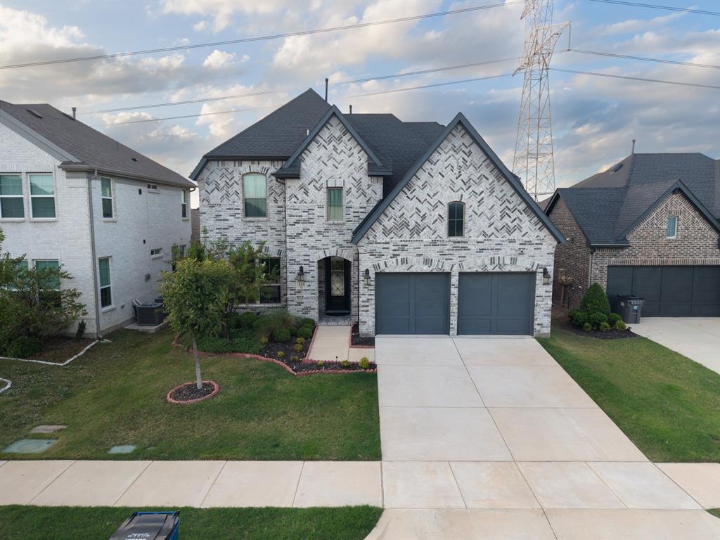Two-story brick exterior with a multi-gabled roofline, an arched entryway, and an attached two-car garage
