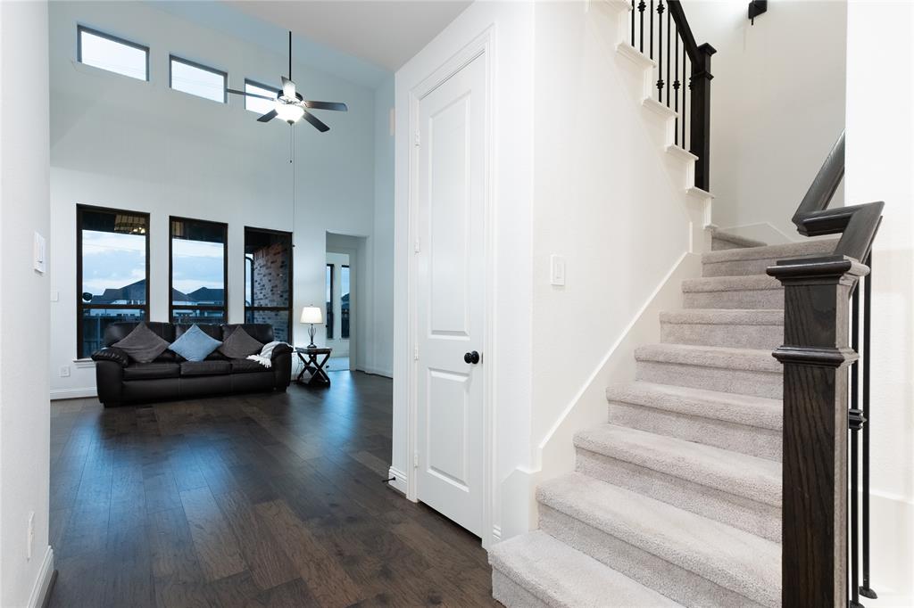 Vaulted ceilings, wood-finish flooring, staircase with carpeted treads and dark-stained wood railings, and oversized vertical windows