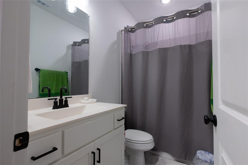 Bathroom featuring a white vanity with matte black hardware, a rectangular sink, a large wall-mounted mirror, and a combination tub and shower