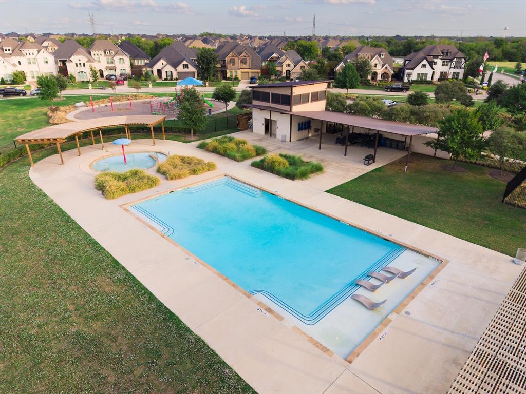 Community amenities including a swimming pool with a tanning ledge, a children's splash pad, a shaded pergola, a clubhouse building, and a playground