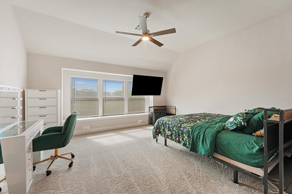 Vaulted ceilings, expansive three-panel window configuration, neutral carpeting, and a central ceiling fan with integrated lighting