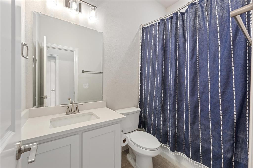 Bathroom featuring a white vanity cabinet, solid-surface countertop with an integrated rectangular sink, wall-mounted mirror, three-light fixture, and a tub-shower combination with a brushed-metal finish faucet