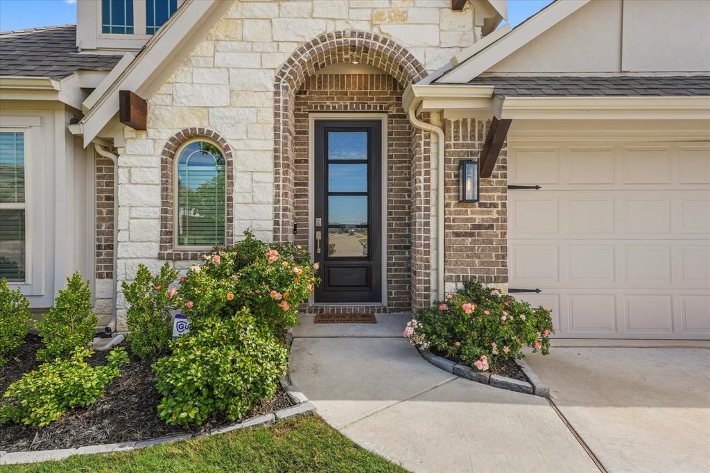 Exterior facade featuring stone and brick masonry, an arched entryway with a multi-pane glass door, and a concrete walkway
