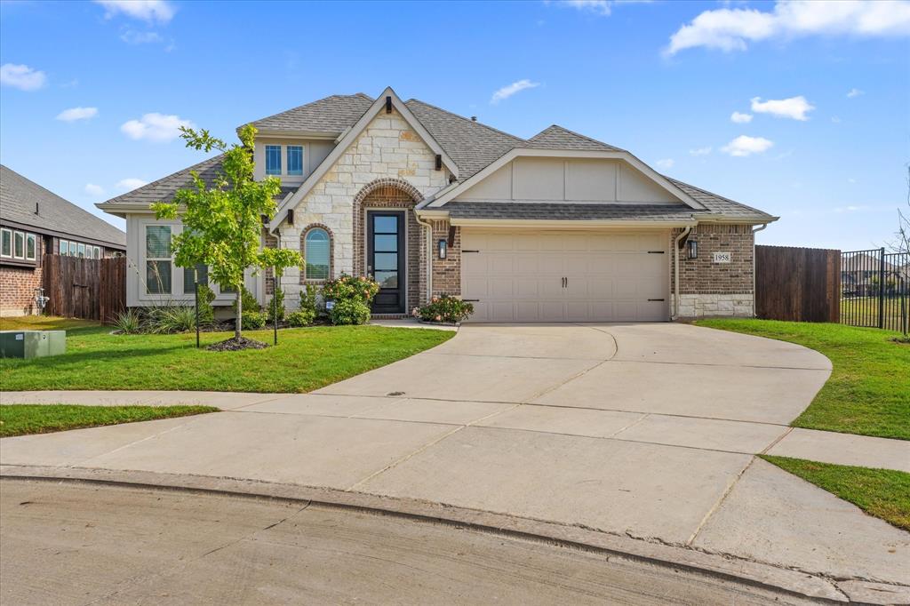Exterior facade featuring a combination of stone and brick masonry, arched entryway, multi-pane glass front door, and a two-car attached garage Exterior facade featuring a combination of stone and brick masonry, arched entryway, multi-pane glass front door, and a two-car attached garage