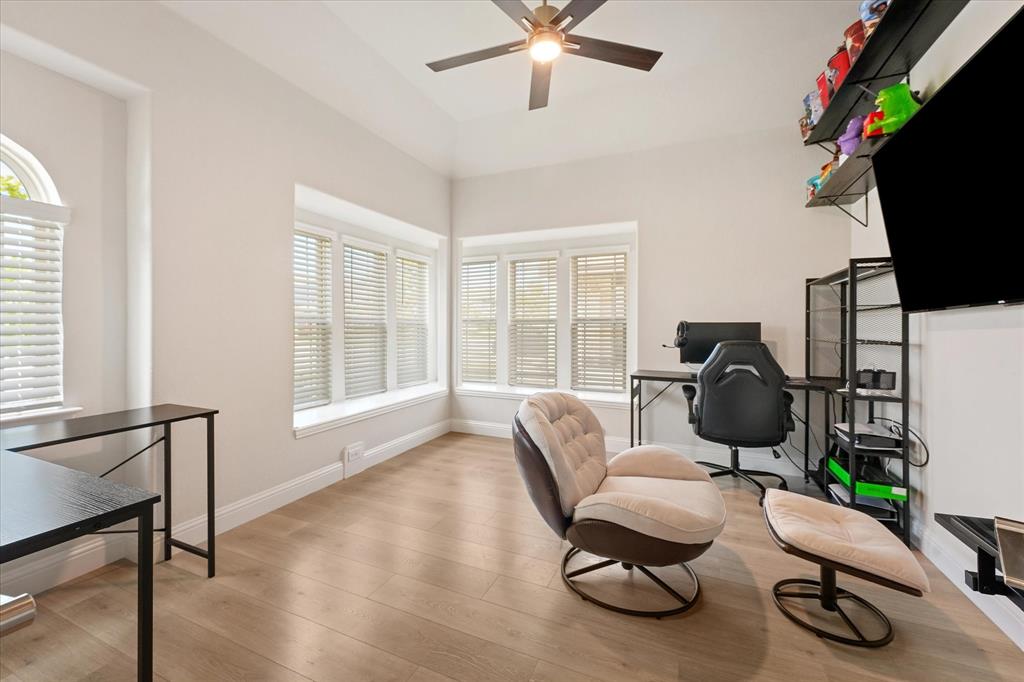 Office Room featuring wood-finish flooring, recessed window bays, multi-pane windows with integrated blinds, and a ceiling-mounted fan with light fixture