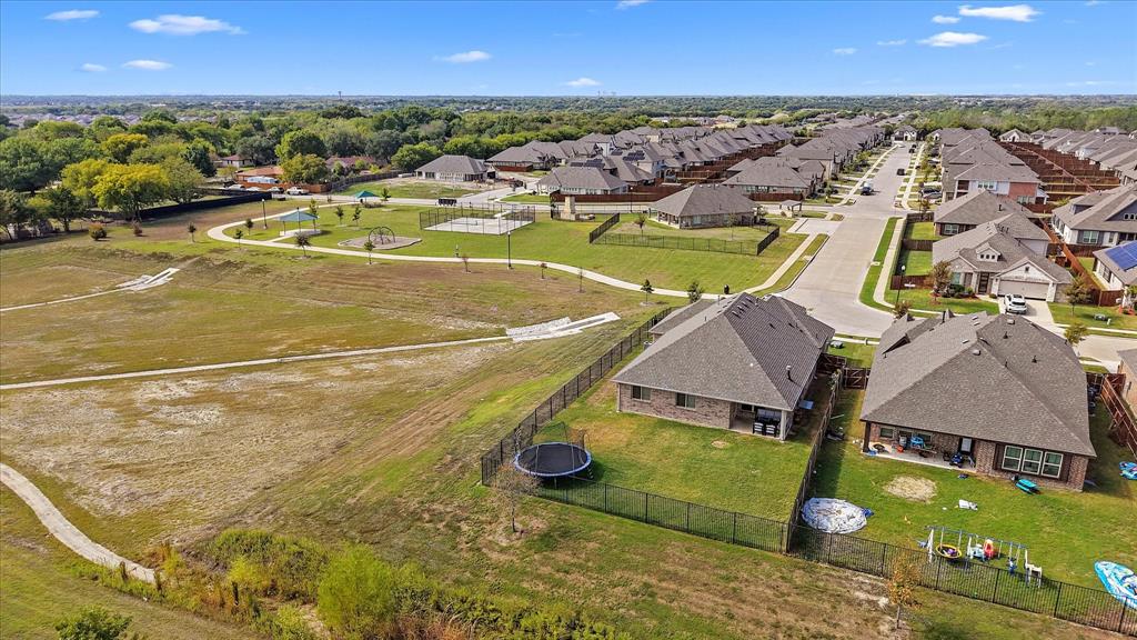 View of park and community center Aerial perspective featuring multi-pitched shingle roofing, brick masonry exterior, perimeter fencing, and concrete walking paths