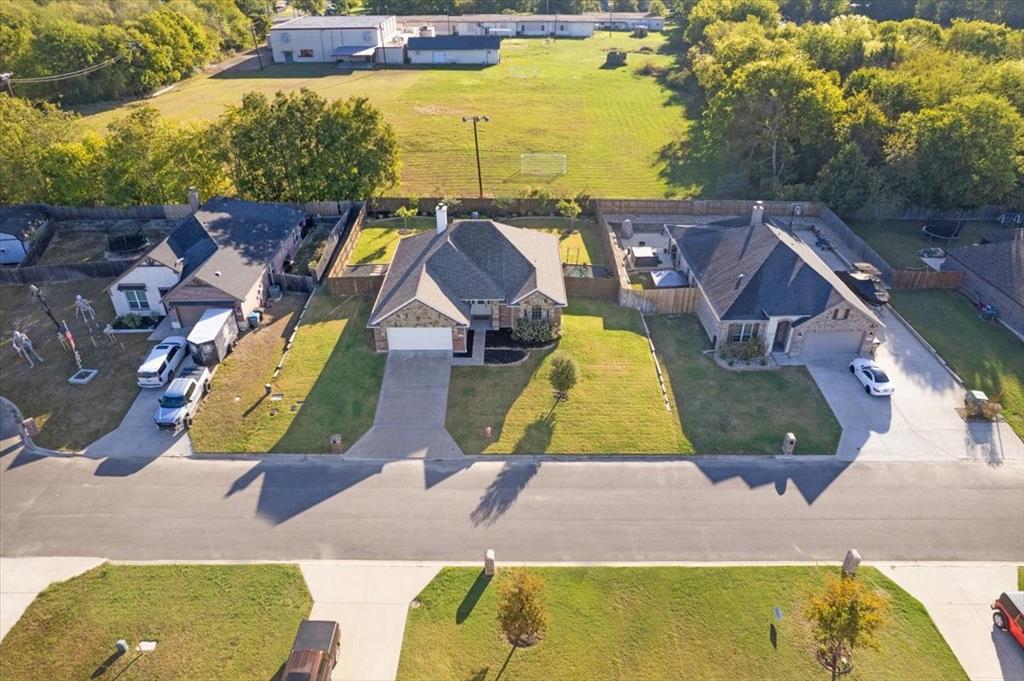 Aerial perspective featuring a multi-gabled roofline, brick and stone exterior, attached two-car garage, concrete driveway, and landscaped front lawn