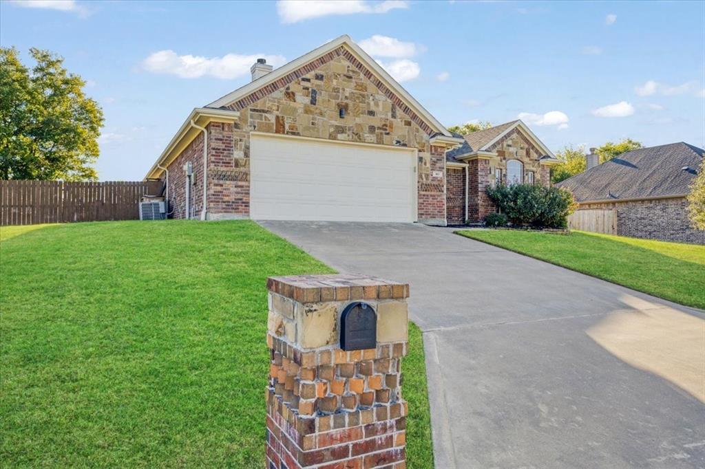 Single-story residence featuring a mixed stone and brick facade, attached two-car garage, concrete driveway, and a matching stone-clad mailbox post