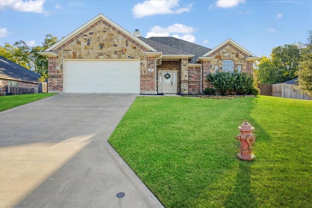 Single-story residence featuring a partial stone and brick veneer exterior, arched entryway, concrete driveway, and gabled roofline
