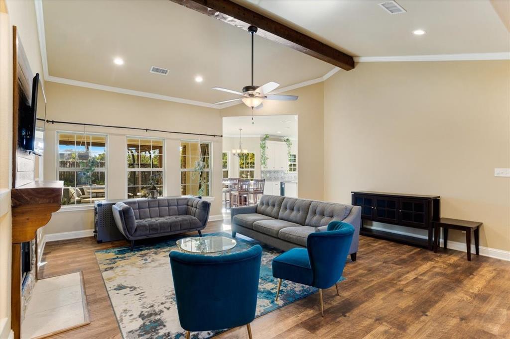 Vaulted ceiling featuring an exposed wood beam, recessed lighting, wood-finish flooring, and a stone-accented fireplace