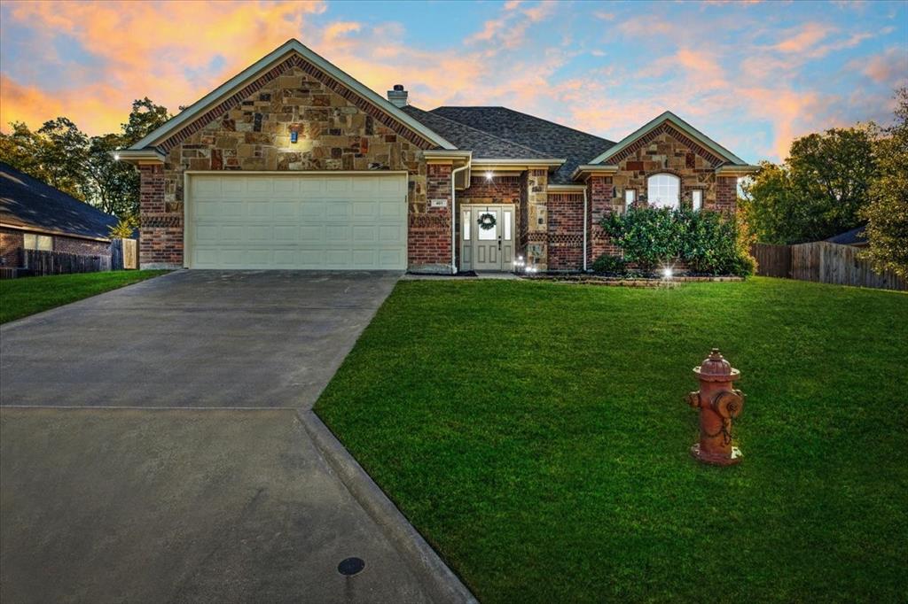 Single-story exterior featuring multi-toned stone and brick masonry, a covered entryway, an arched window, and an attached two-car garage
