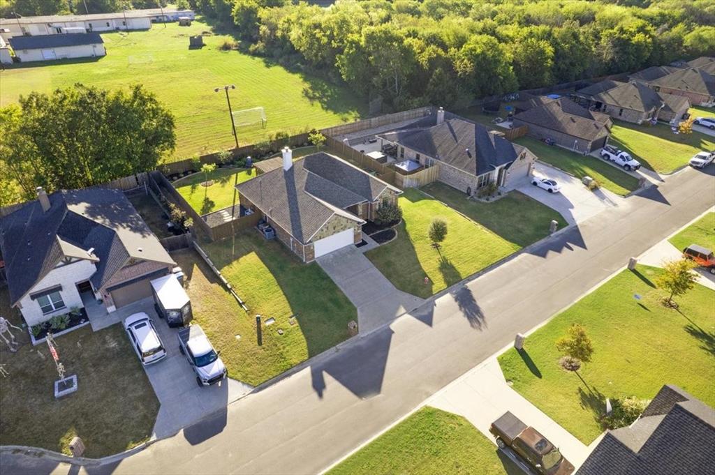 Aerial perspective featuring residential lots with concrete driveways, masonry and siding exterior finishes, composition shingle roofing, and established perimeter fencing