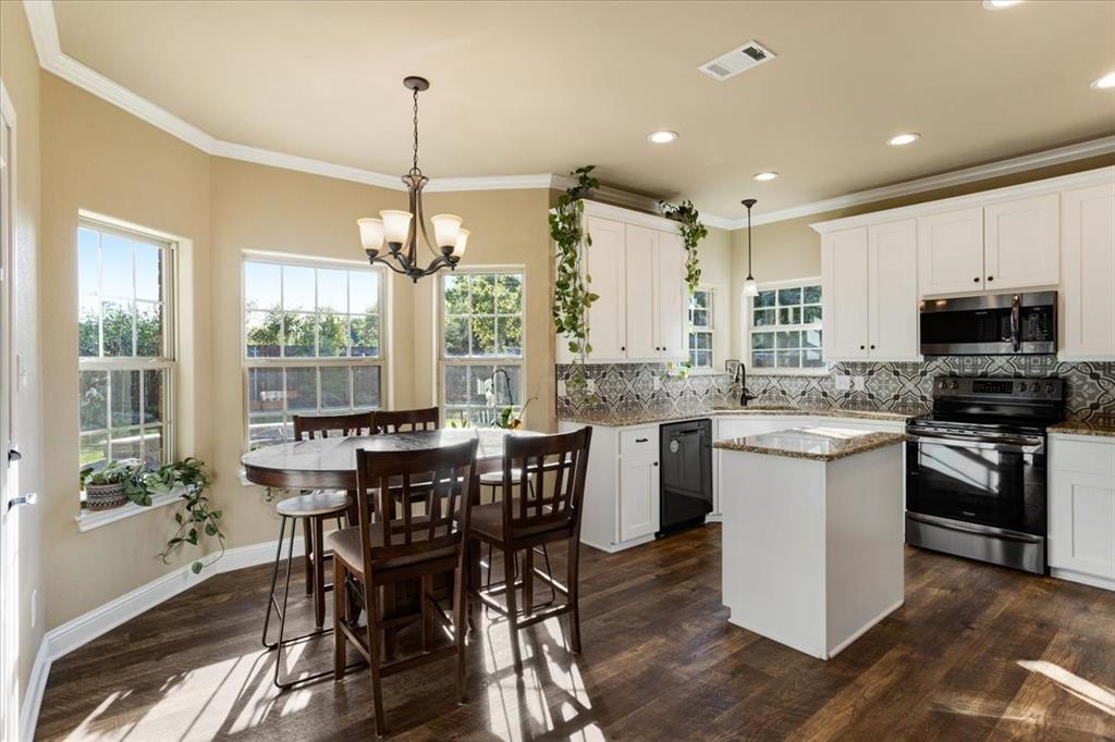 Kitchen featuring white shaker-style cabinetry, a central island, stone-finish countertops, patterned tile backsplash, and wood-finish flooring