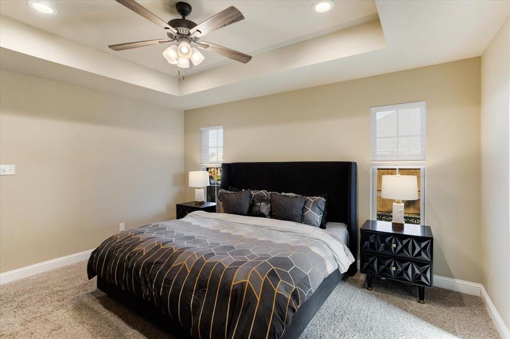 Tray ceiling with integrated recessed lighting, central ceiling fan, and carpeted flooring