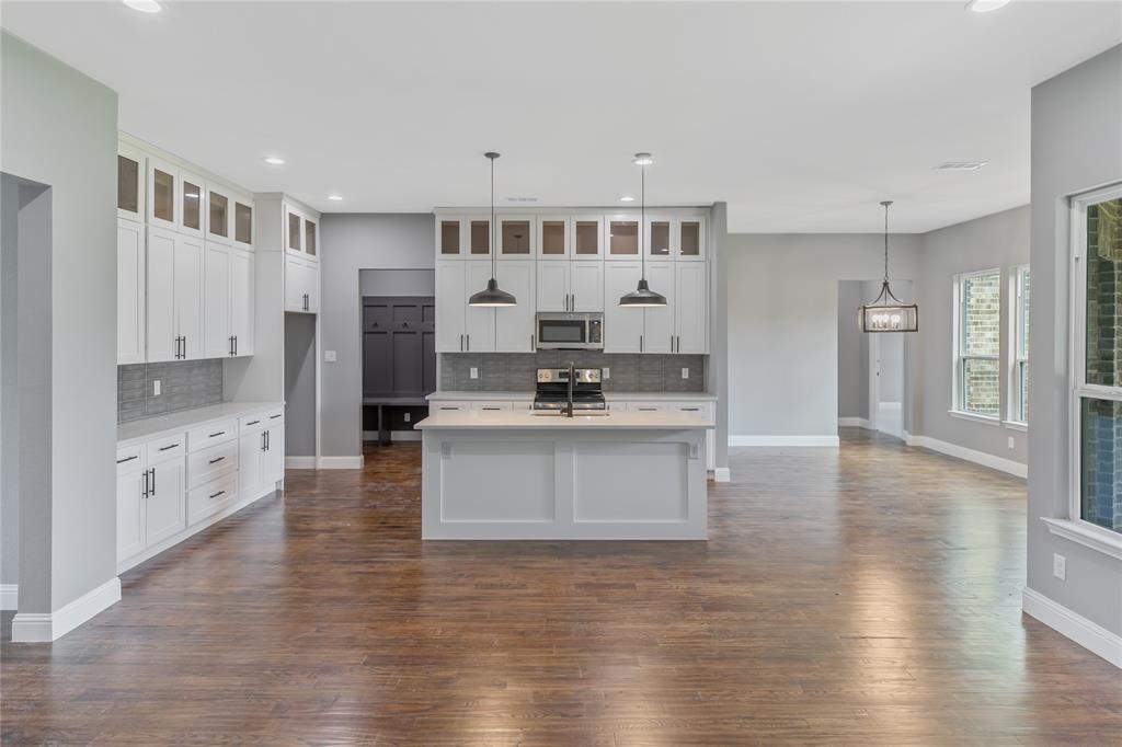 Kitchen featuring backsplash, glass insert cabinets, hanging light fixtures, recessed lighting, and appliances with stainless steel finishes