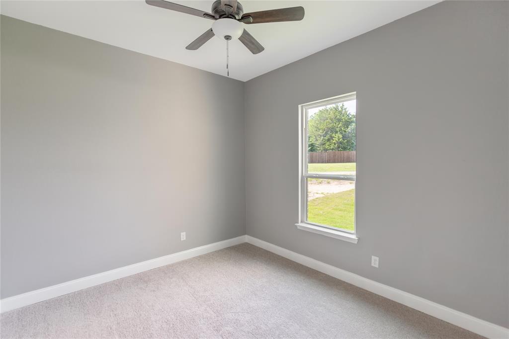 Carpeted empty room with baseboards and a ceiling fan