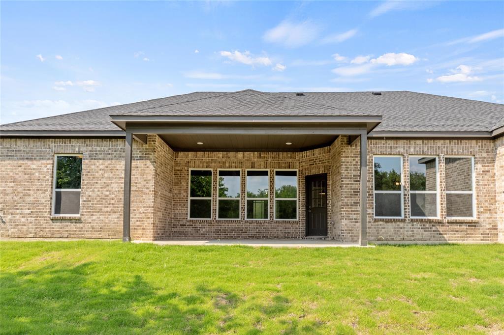 Rear view of property featuring a patio, brick siding, and a lawn