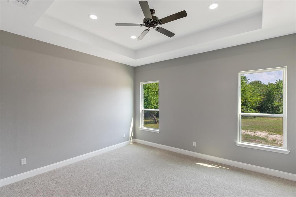 Empty room with a tray ceiling, carpet floors, recessed lighting, and ceiling fan